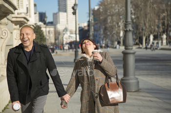 senior Caucasian couple strolling and laughing holding hands