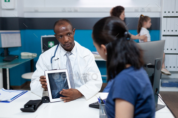 African american pediatrician doctor holding tablet computer explaining radiography expertise