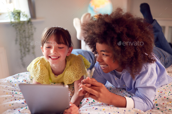 Girl And Boy In Bedroom Lying On Bed Using Digital Tablet Together ...