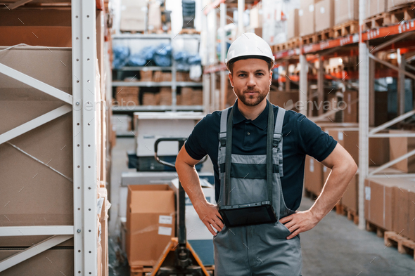 Standing and posing. Employee in uniform is working in the storage at daytime - Stock Photo - Images