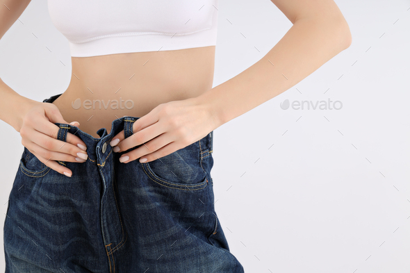 Concept of weight loss with slim young woman on light background - Stock Photo - Images