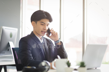 Business Asian man working using smart phone with smiling and confident emotion.