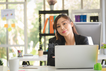 Business Asian woman working with her laptop with smiling in modern interior office workplace.
