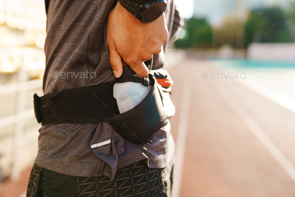 Young white sportsman drinking water while working out on stadium - Stock Photo - Images