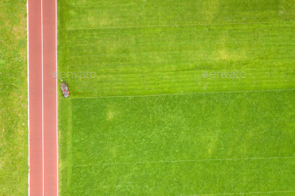 Aerial view of small figure of worker cutting green grass - Stock Photo - Images