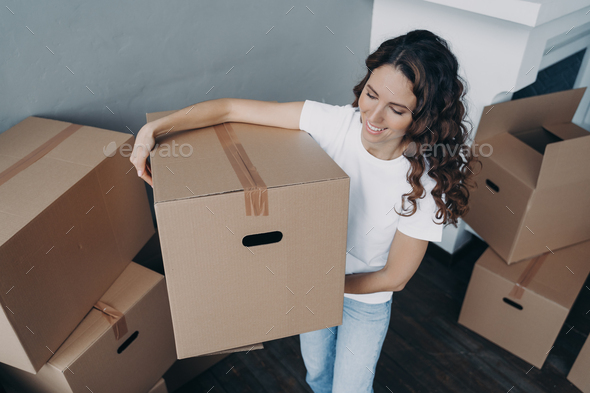 Woman is moving to better place and carrying box. Happy european lady purchasing real estate.