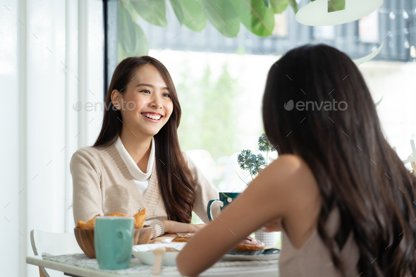 Two young Asian women friends talking at a coffee shop - Stock Photo - Images