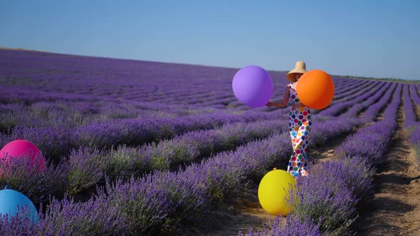 Woman in a Multicolored Suit with Circles and a Hat Holds Large Inflatable alt
