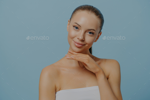 Cosmetic procedures. Pleased woman touching healthy moisturized facial skin after beauty treatment - Stock Photo - Images