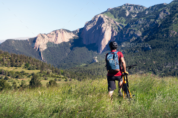 man with backpack and bike observes the mountains - Stock Photo - Images