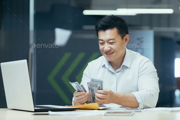 Successful asian investor counting dollars money cash sitting in office