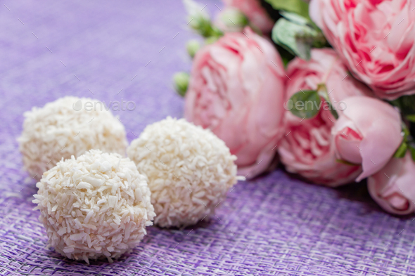 Homemade coconut candy on a background of pink flowers. Sweets for