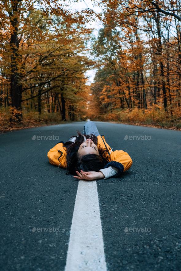 Confidence woman lying on the road with autumn tree around. New life, path choice