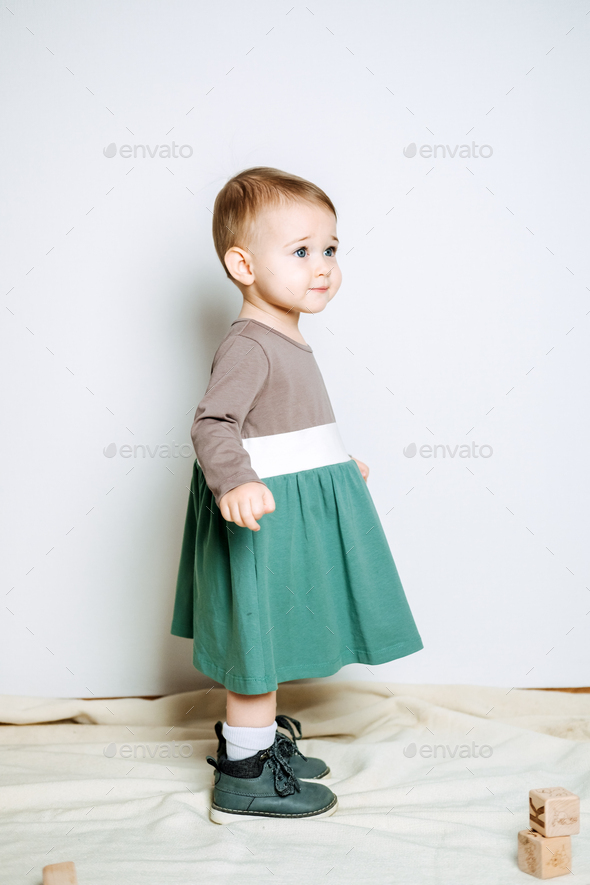 Baby fashion. Unisex color clothes for babies. Cute baby girls in neutral color palette cotton dress