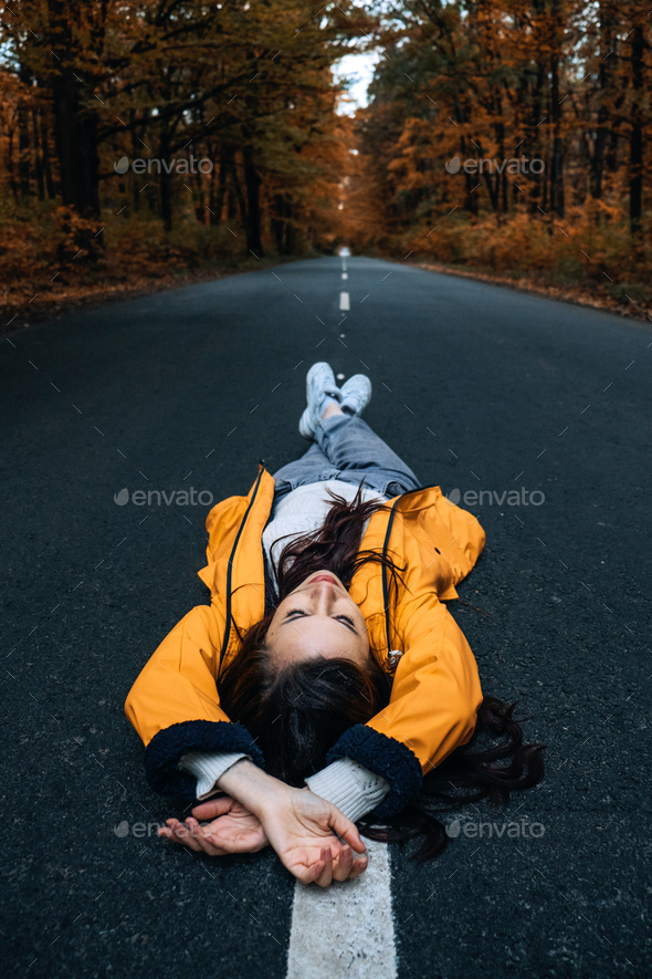Confidence woman lying on the road with autumn tree around. New life, path choice