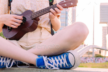 hands of young woman in sneakers playing ukulele