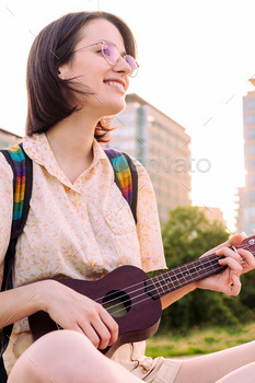 vertical portrait of smiling woman playing ukulele