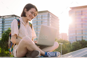 smiling young woman at city typing on a computer