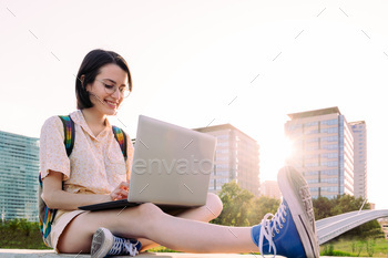 happy young woman in the city typing on a laptop