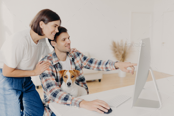 husband points into monitor of computer, asks for useful advice in wife what better to buy