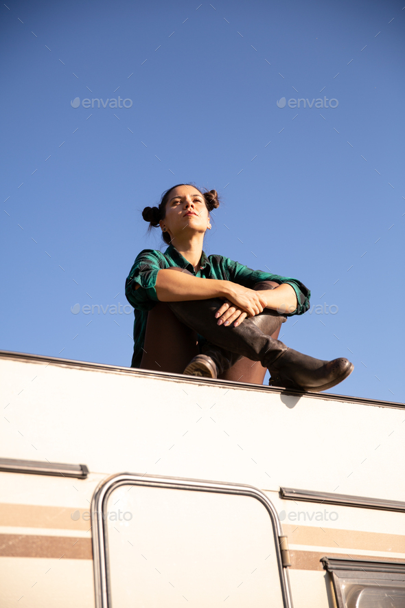 Young girl relaxing on the roof of a retro camper - Stock Photo - Images
