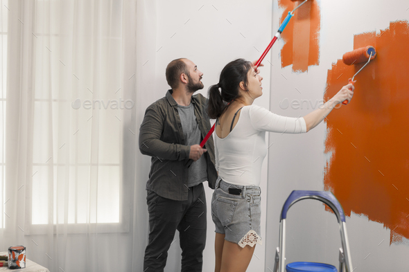 Man and woman painting with orange paint