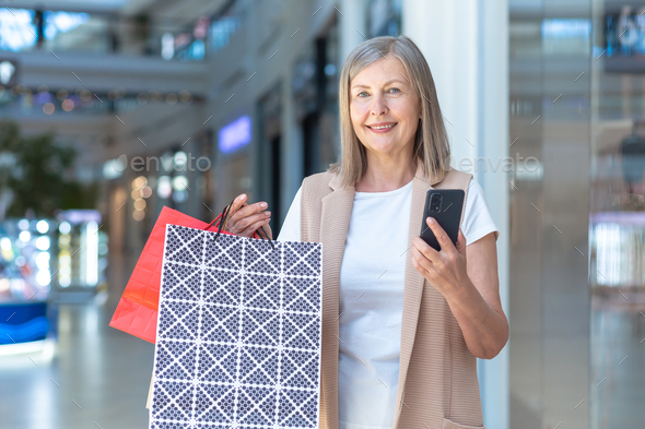 Portrait of a beautiful senior woman shopping in the mall. She talks on the phone