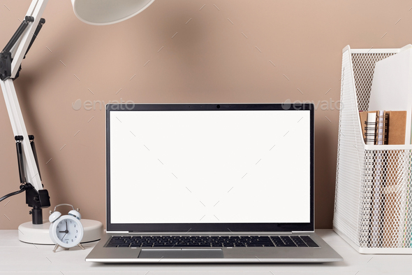 Empty laptop screen, desktop organizer with desk lamp and office supplies