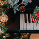 a Christmas gift on piano keys and a decorated Christmas tree with lights - PhotoDune Item for Sale