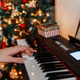 close up of many hands plays on Piano Keys with Christmas tree - PhotoDune Item for Sale