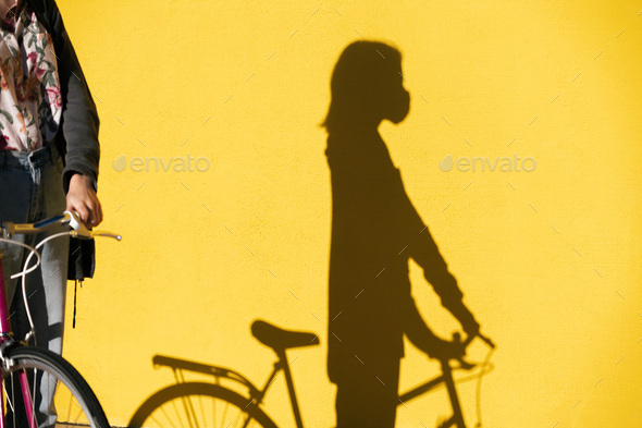shadow of a woman on a bicycle wearing mask