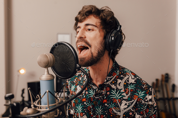 Male singer on headphones singing at recording home studio