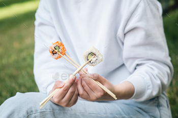 Close-up, woman eating sushi in summer in the park.
