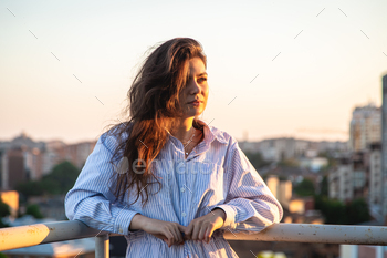 Portrait of a young woman on the balcony at sunset.