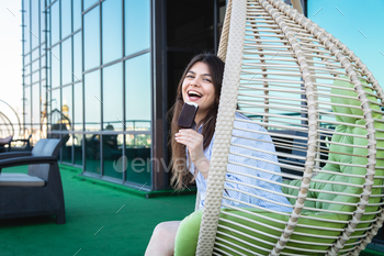 Happy young woman with chocolate ice cream in a hammock.