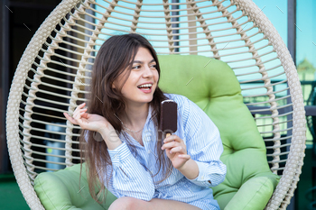 Happy young woman with chocolate ice cream in a hammock.