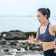 Young asian woman runner resting after workout running in beach seaside. - PhotoDune Item for Sale