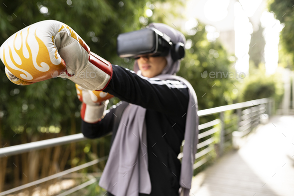 muslim woman with hijab practicing boxing outdoors, in a simulation with virtual reality  - Stock Photo - Images