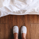 Male feet in white hotel slippers standing in front of the bed - PhotoDune Item for Sale