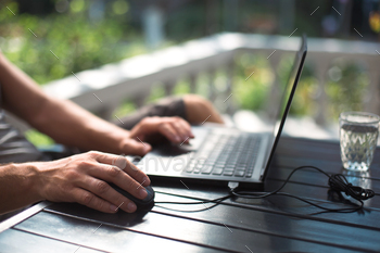 Working at a laptop in the outdoor courtyard - men's hands close-up. Home office, remote work