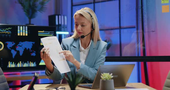 Businesswoman in Wireless Headset Sitting in front of Laptop During Video Meeting alt
