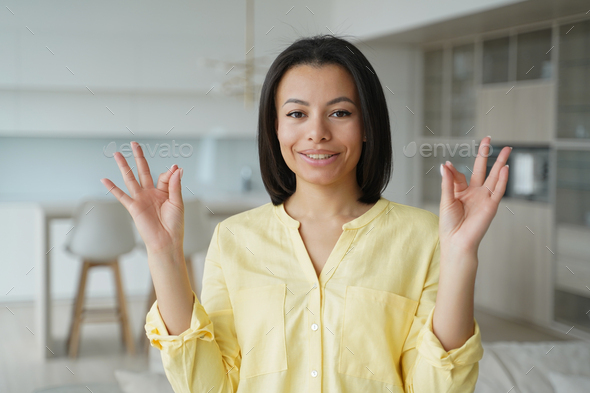 Female keeps calmness, makes mudra hand gesture, practice yoga at home. Stress relief, wellness