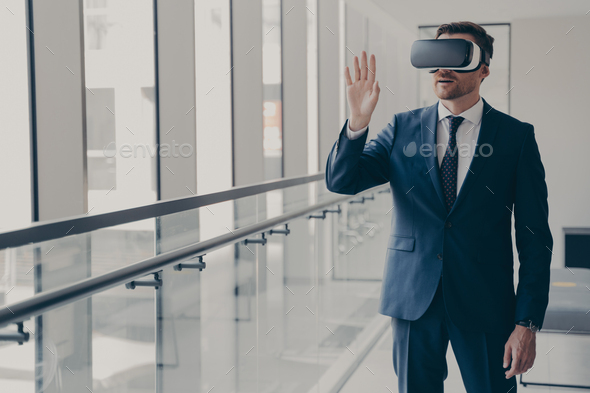 Excited office worker dressed in formal clothes managing business project through virtual reality