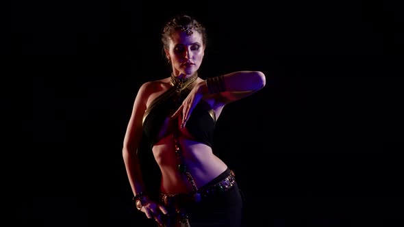 A Woman Dancing an Oriental Dance in a Studio on a Black Background Makes Beautiful Movements with alt