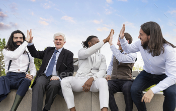 multiracial businessmen shake hands celebrating outdoors