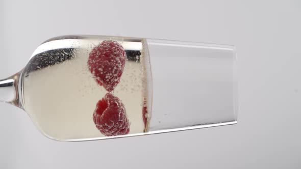 Vertical video, Close-up: strawberries float in a glass of bubbling champagne alt