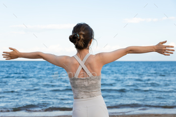 Relaxed woman stretching arms brea fresh air on the beach, freedom concept