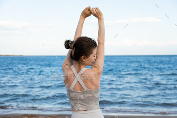 Relaxed woman breathing fresh air and stretching arms on beach, freedom concept