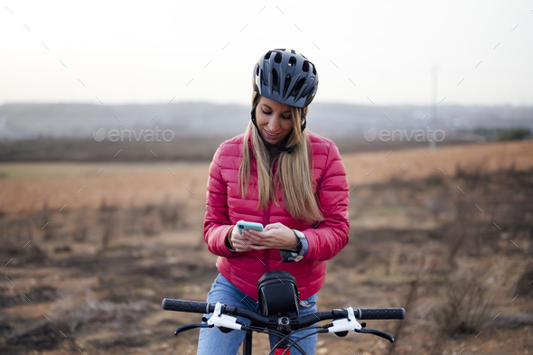 Happy blonde woman on bike checking mobile phone in the countryside - Stock Photo - Images