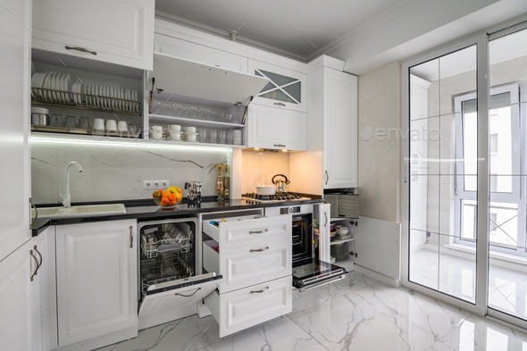 Luxurious white modern kitchen interior, drawers pulled out, dishwasher\'s door open